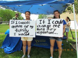 Students standing under tent with signs