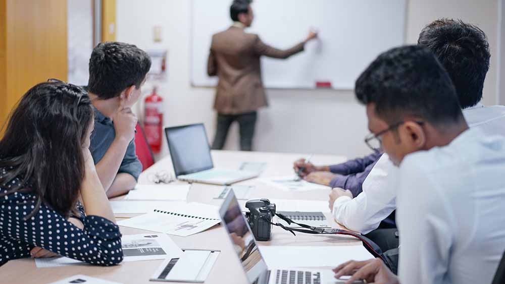 Man at white board in front of class